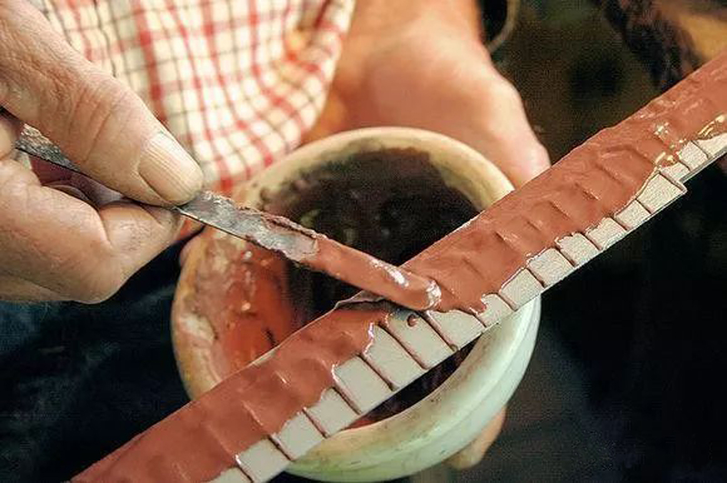 Swordsmith applying clay during katana clay tempering process